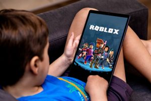 Niño chico juega al roblox en una tableta en un sofa negro