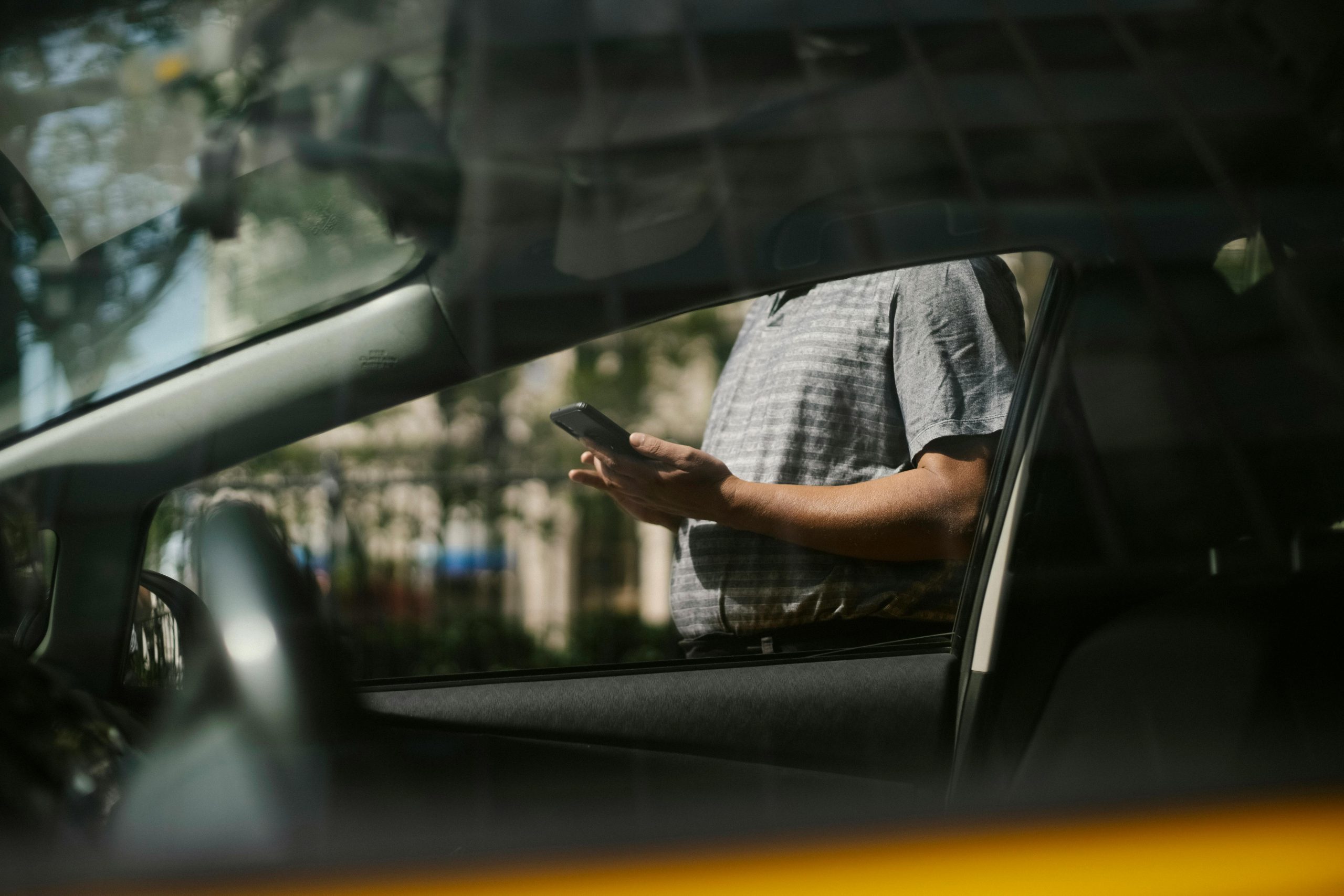 Hombre usando un smartphone fuera de un coche.